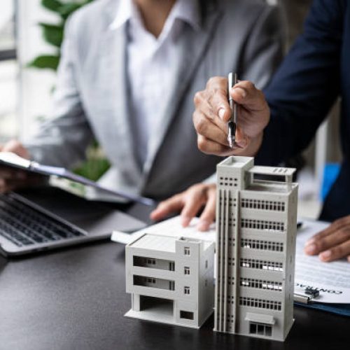 real estate agent Describe house designs to view house plans and purchase contracts. wooden house at modern office ​​Business success, signing a contract to buy a house with land and insurance with the concept of renting a house